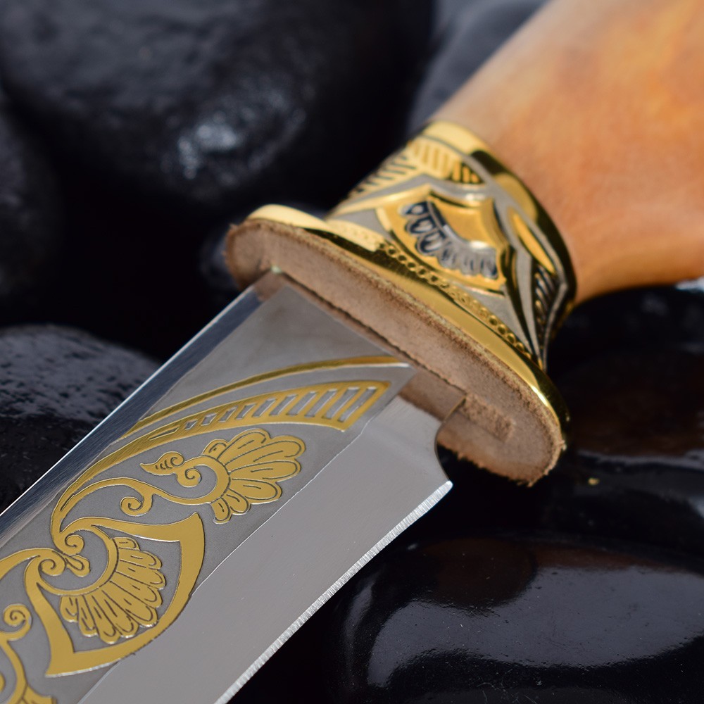 The blade of a knife with a gold pattern