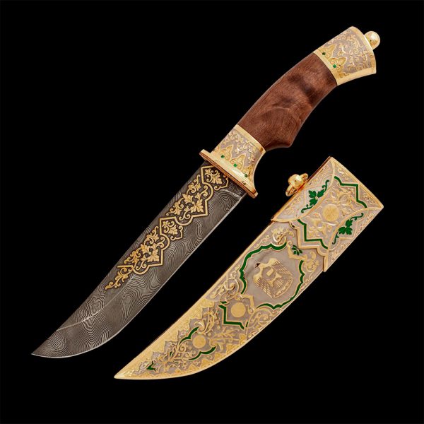 A knife made of damask steel and a wooden hilt is decorated with a golden falcon - the emblem of the UAE. Gift for falconry