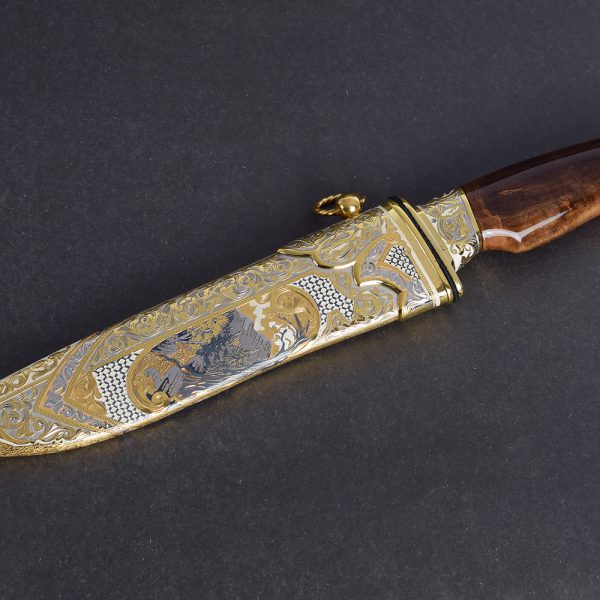 Handmade decorated knife in golden scabbard. The metal sheath is marked with a cutout from the surface using a cutter.