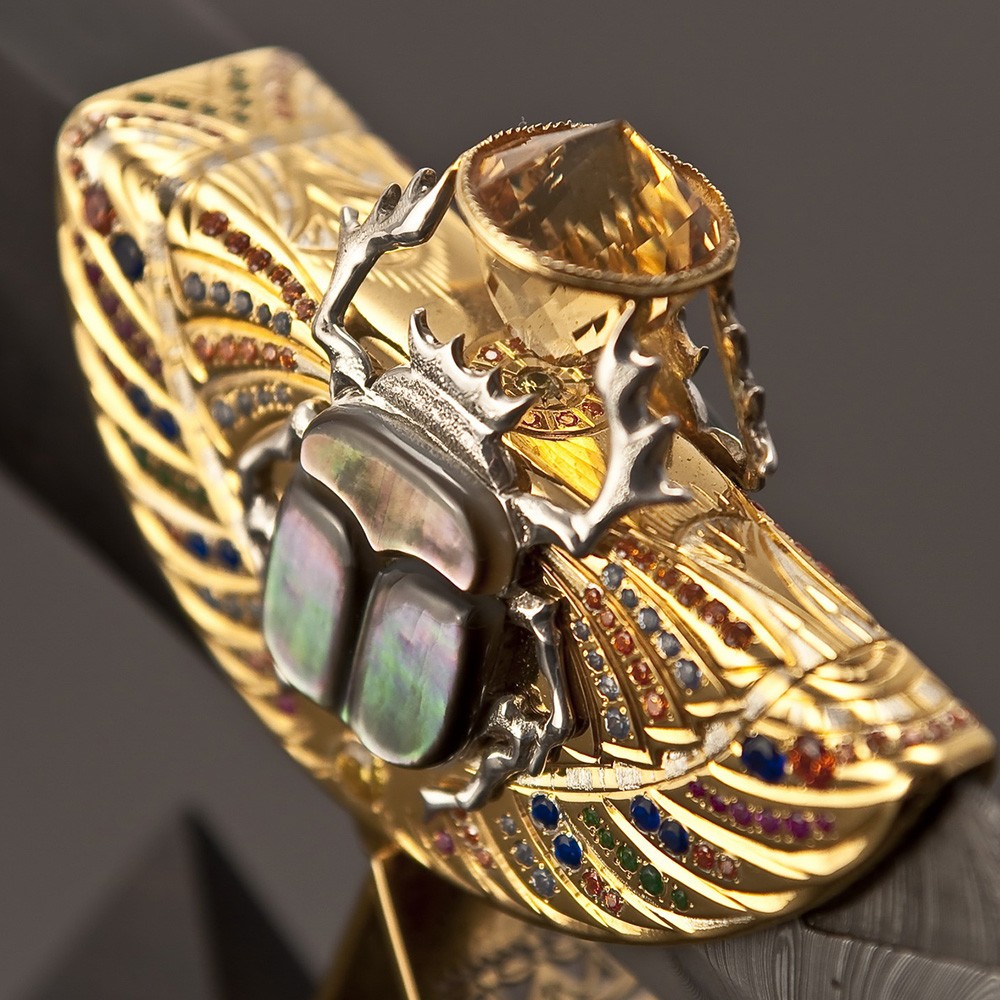 In the legs raised to the sky, the scarab holds a light, 96-faced citrine stone with the energy of the sun, purity of thoughts and healing power inside. Its mother-of-pearl wings sparkle in the sun, reflected in the faces of the great Egyptian pyramids.