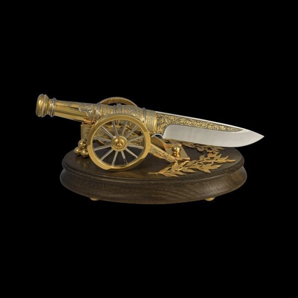 Golden gun composition. Handmade knife on a stand in the form of a gun. Decoration of the interior of the office.