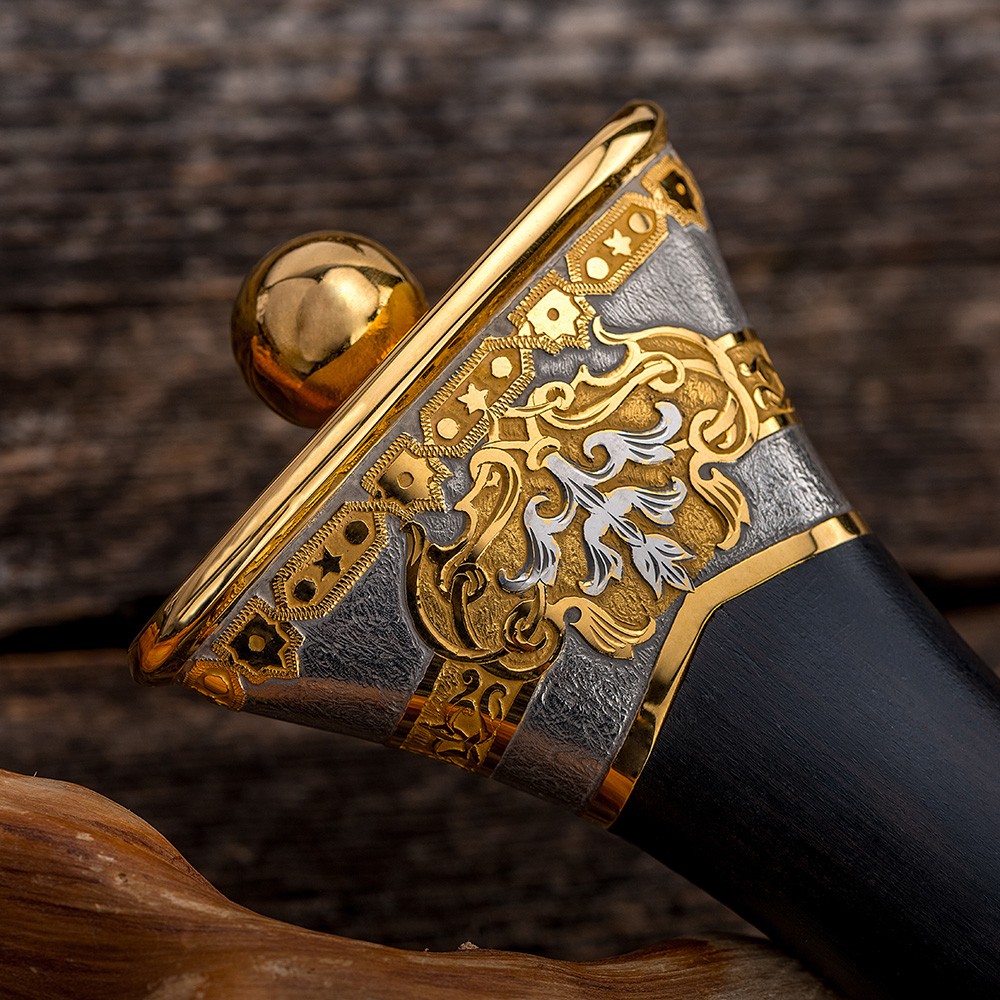 The handle of a dagger expands to the end of its end. The surface of the metal elements is decorated with carvings made by hand with a cutter.