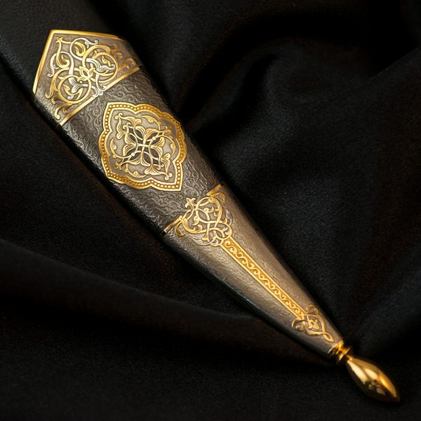 The metal tip of the dagger scabbard with an amazing relief ornament made by an engraving artist manually using a cutter and a microscope.
