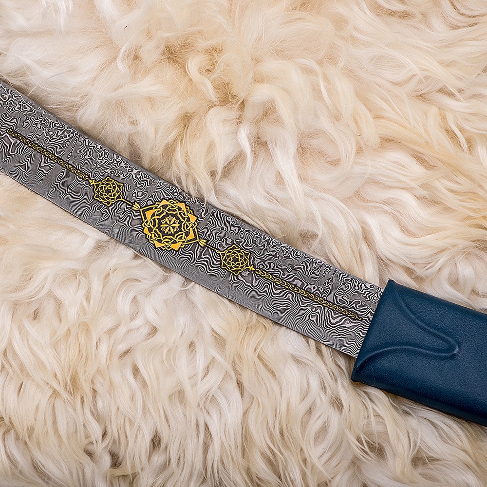 The blade of the Arabian sword with a beautiful damask steel pattern decorated with gold oriental ornaments.
