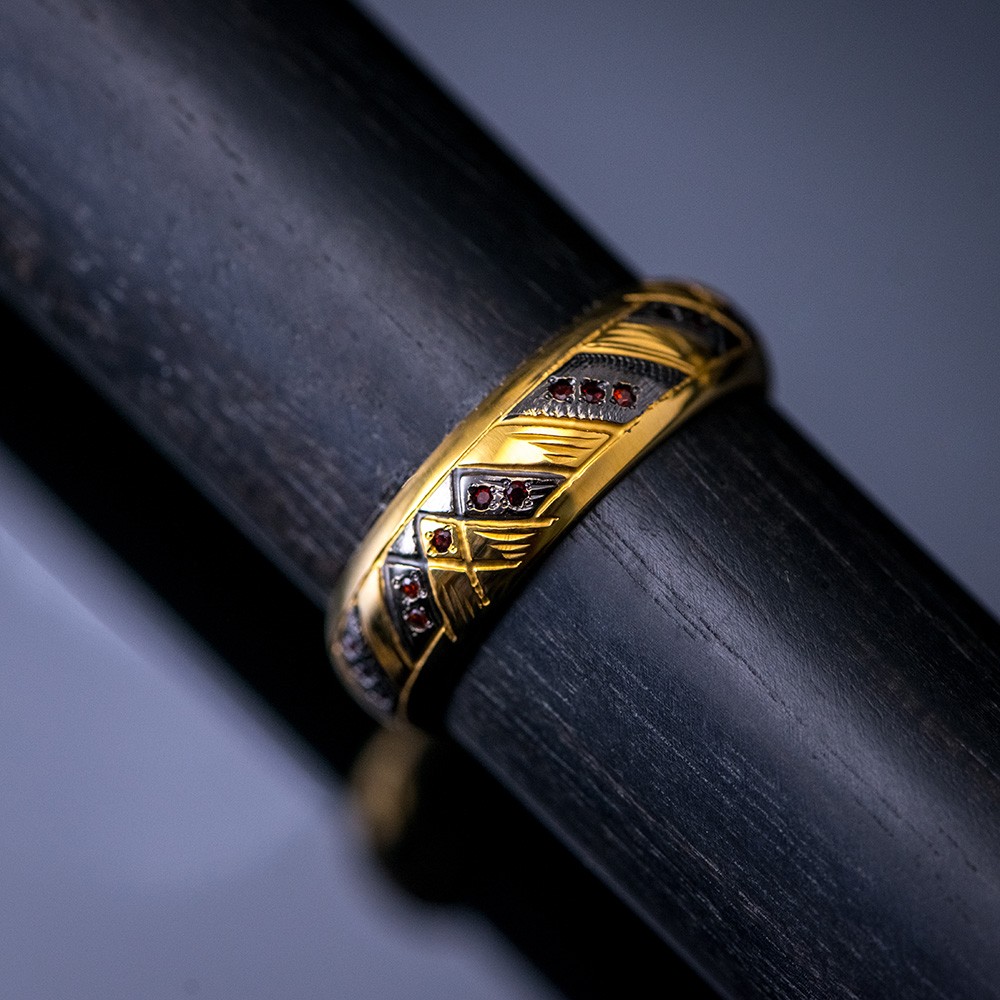 Golden ring with red crystals on a wooden cane trunk.