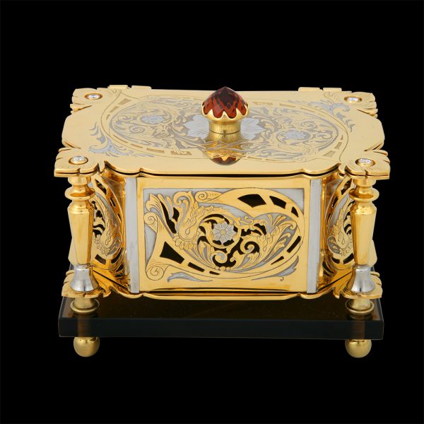Golden casket - Lady. Decorated with patterns and cut-outs. A large red crystal is mounted on the lid.