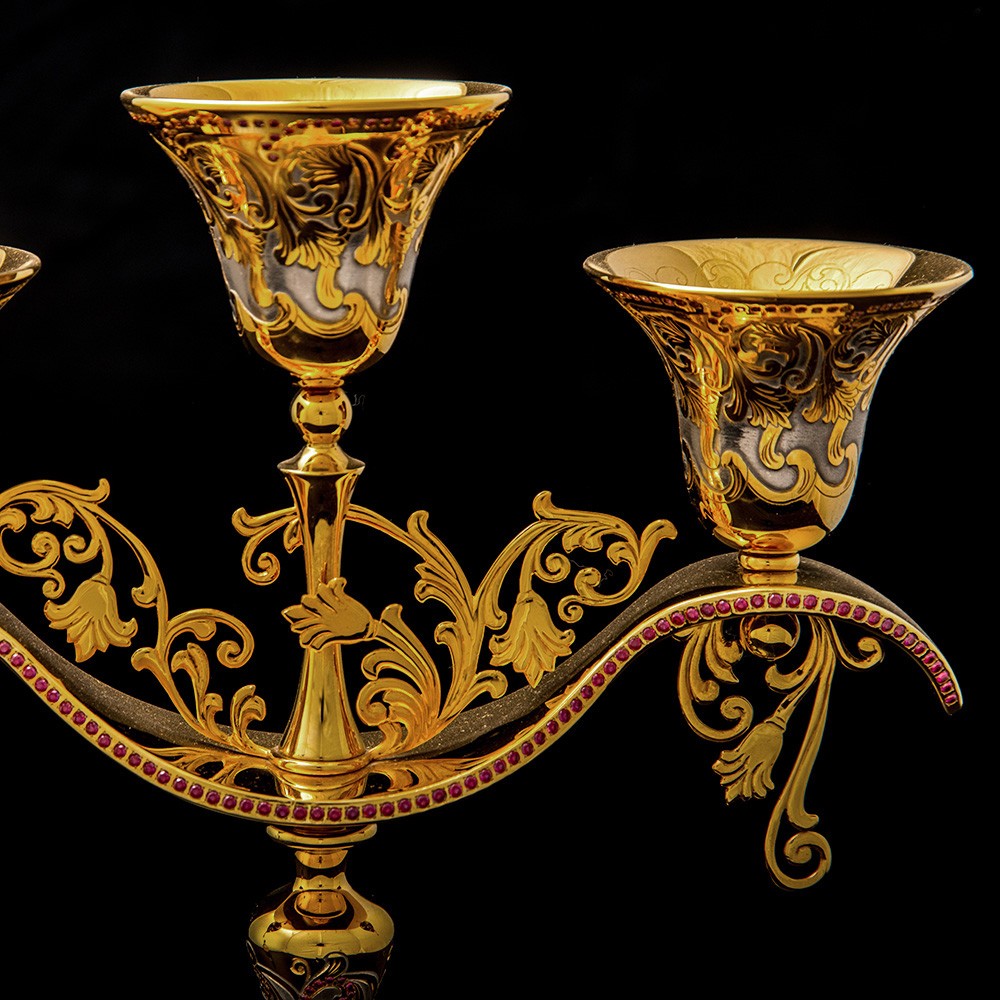 The candle holder bowls are inverted bells placed on a single arc, decorated with slotted elements and inlaid with rhodolites (610 stones) which are also called “pink garnet.”