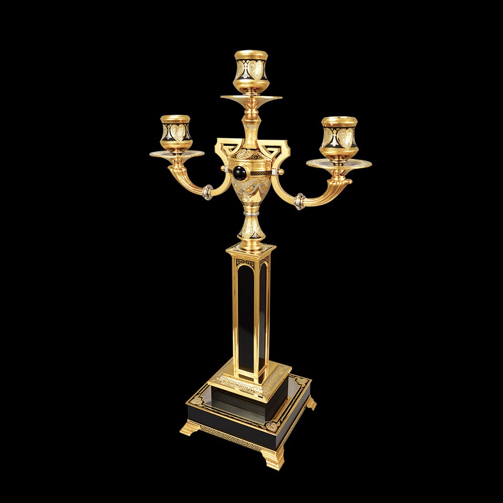 Gold candelabra for three candles on a stone base.