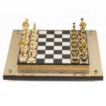 لوحة الشطرنج. شطرنج كلاسيكي مصنوع يدويًا من الحجر والذهب. في الزوايا، تم تزيين لعبة الشطرنج بكبوشن الملكيت.