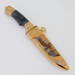 Knife in a golden sheath with an eagle pattern