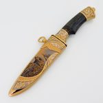 Knife in a golden sheath with an eagle pattern