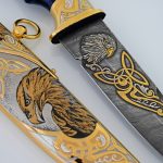 Pattern of Damascus steel knife with gold coating and scabbard with the image of a bird of prey