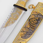 mirrored knife blade and golden scabbard with the image of a bear