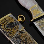 mirrored knife blade and golden scabbard with the image of a bear